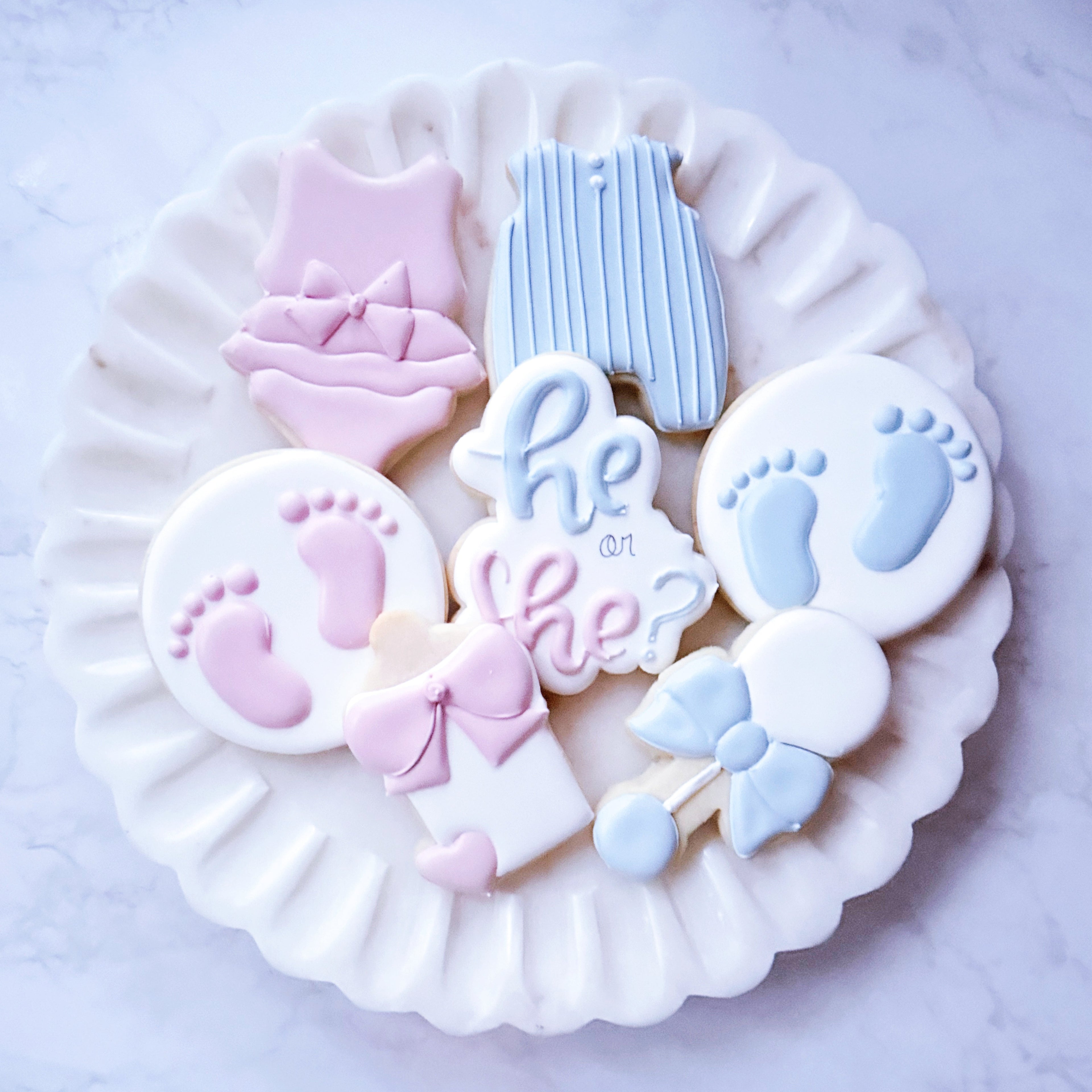 Decorative cookies with baby-themed designs on a white plate.