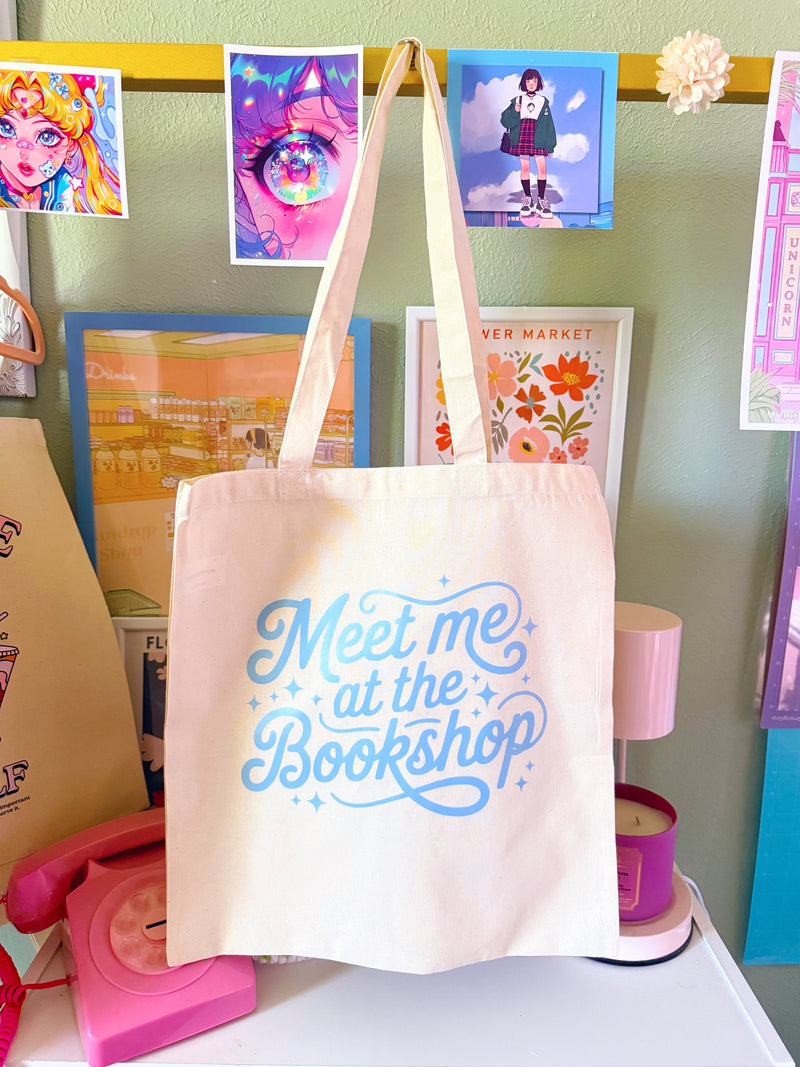 Tote bag with 'Meet me at the Bookshop' text in a colorful room with posters on the wall.