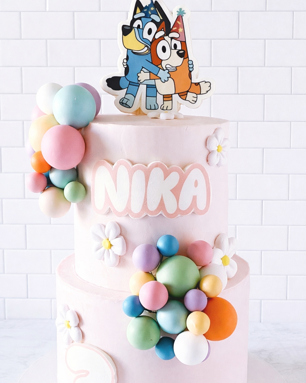 Decorative cake with colorful balloons and cartoon character on a white background